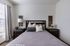Inviting bedroom with plush bedding, elegant furnishings, and ample natural light through large windows.