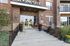 Welcoming leasing office entrance with elegant brick facade and charming seasonal decor, inviting potential residents.