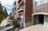 Charming brick apartment building with private balconies, lush greenery, and a welcoming entrance.