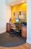 Chic home office nook with modern desk, ergonomic chair, and stylish artwork against a vibrant yellow wall.