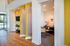 Bright, modern apartment with wood flooring, stylish yellow accents, and a cozy office space overlooking a sunlit pool area.