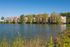 Beautiful lakeside apartment complex surrounded by lush greenery, offering serene views and modern living spaces.