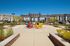 Vibrant outdoor community area with colorful Adirondack chairs under a pergola, surrounded by modern apartment buildings and lush greenery.