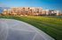 Elegant modern apartment complex bathed in golden sunset light, surrounded by lush green lawns and scenic pathways.
