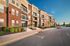 Modern apartment building with stylish brick facade, balconies, and welcoming leasing office entrance set against a clear blue sky.