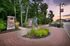 Charming garden entrance with stone pillars, vibrant greenery, and playful statue, set against a serene evening sky.