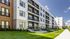 Modern apartment building with stylish design, featuring private balconies, lush greenery, and a well-maintained exterior under a clear blue sky.