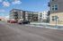 Modern apartment complex featuring sleek architectural design, ample parking, and convenient electric vehicle charging stations under a clear blue sky.