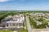Charming aerial view of a modern residential complex surrounded by lush greenery and a lively community, offering a harmonious blend of urban living and natural serenity.