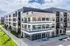 Modern apartment building with sleek glass balconies and stylish exterior design, surrounded by lush greenery and open pathways.