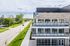 Modern apartment building with expansive balconies and a scenic tree-lined street view, showcasing a blend of urban living and natural beauty.
