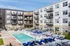Modern apartment complex featuring a stylish outdoor pool area with sun loungers and elegant balconies overlooking the courtyard.