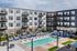 Modern apartment complex with a sparkling pool, stylish lounge chairs, and inviting balconies, offering the perfect blend of relaxation and comfort.