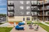 Modern apartment exterior featuring stylish balconies and a vibrant communal outdoor space with comfortable seating and fire pits.