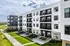 Modern apartment building with sleek design, spacious balconies, and manicured landscaping on a sunny day.