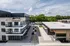 Modern apartment complex with spacious balconies and lush green surroundings on a sunny day, featuring ample parking and stylish design.