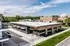 Contemporary commercial space with expansive glass fronts, surrounded by lush green landscape and clear blue skies.