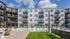 Modern apartment complex with sleek balconies, inviting pool area, and stylish outdoor seating under a bright blue sky.