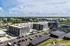 Aerial view of a modern apartment complex with sleek design, ample parking, and lush green surroundings.