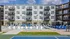 Modern apartment complex with balconies overlooking a pristine pool, surrounded by stylish loungers and umbrellas, complementing the vibrant atmosphere.