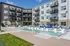 Modern apartment complex with a refreshing pool, stylish sun loungers, and vibrant outdoor seating, showcasing sleek contemporary architecture.