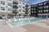 Modern apartment complex featuring a pristine swimming pool with luxurious loungers and shaded seating areas, perfect for relaxation and leisure.