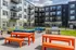 Modern apartment complex featuring vibrant outdoor seating, stylish balconies, and barbecue area, perfect for social gatherings.