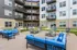 Modern apartment complex featuring a chic outdoor lounge with vibrant blue seating, fire pits, and sleek balconies.