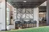Modern lounge area featuring a sleek bar counter with stylish bar stools, creative wall shelving displaying colorful sneakers, and ample natural light from large windows.