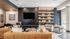 Modern living room with chic leather sofas, sleek shelving, and large wall-mounted TV, offering a stylish and cozy ambiance.
