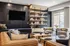 Modern and inviting living room with a stylish leather sofa, contemporary armchairs, and a sleek wall-mounted TV. Elegant open shelves feature books and decorative accents, creating a cozy and sophisticated ambiance.