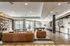 Modern apartment lounge with stylish leather sofas, elegant open shelving, and a pool table, illuminated by natural light.