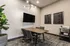Elegant meeting room with modern decor, featuring a sleek wooden table, stylish chairs, and a chic wall-mounted television, accentuated by unique ceiling lighting and decorative wall art.