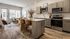 Contemporary open-concept kitchen and living area with stylish wood flooring, elegant island seating, and abundant natural light.