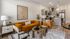 Contemporary living room design featuring a vibrant mustard sofa, chic patterned rug, and an elegant open kitchen with stylish decor.