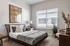 Bright and cozy bedroom with modern decor, featuring a large window, stylish bed, and elegant wall art.