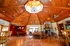 Captivating living space with a stunning octagonal wooden ceiling, elegant chandelier, cozy stone fireplace, and rich hardwood floors.