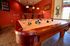 Inviting game room with a stylish pool table, cozy red walls, and elegant lighting perfect for entertaining.