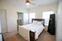 Bright and cozy bedroom with a stylish ceiling fan, elegant wooden bed frame, and natural light streaming through large windows.