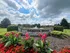 Welcome to Dakota Ridge: Serene community entrance with vibrant flowers, lush greenery, and elegant stone signage under a picturesque sky.