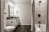 Elegant bathroom with modern fixtures, featuring sleek cabinetry, a spacious countertop, and a stylish bathtub with a rainfall shower.