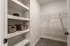 Spacious walk-in closet featuring white shelving with stylish wicker baskets and ample hanging space for ultimate organization.