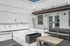 Modern rooftop terrace with sleek outdoor seating, chic planters, and built-in cabinetry under a clear blue sky.
