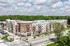 Modern apartment complex with stylish architecture, surrounded by lush greenery and situated on a peaceful street.