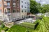 Modern apartment building with elegant balconies, lush landscaping, and a cozy outdoor patio area with seating, perfect for relaxation.