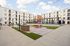 Chic apartment courtyard with modern outdoor lounge area, elegant pergola, and sleek BBQ station set against a stylish building facade.