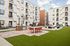 Modern apartment complex courtyard featuring a stylish outdoor dining area, lush green space, and contemporary architecture.