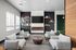 Elegant lounge area featuring plush armchairs, a modern fireplace, and a sleek TV, complemented by wall-mounted bookshelves and large windows.
