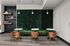 Chic and modern lounge area with rich green velvet seating, elegant marble tables, and warm wooden chairs, complemented by stylish shelving and contemporary lighting.