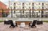 Chic outdoor lounge area with modern wooden flooring, comfortable seating, and stylish overhead string lights, perfect for relaxing and entertaining.